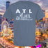 Gray t-shirt with 'ATL' design in front of a cityscape with a Ferris wheel and skyline.