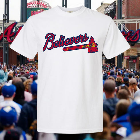 White t-shirt with 'Believers' graphic in front of a sports stadium crowd
