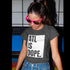 Person wearing a gray t-shirt with 'ATL IS DOPE.' text and pink sunglasses in front of a colorful background.