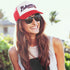 Model wearing red and white Believers Trucker Hat, inspired by Atlanta baseball, adjustable snapback style.