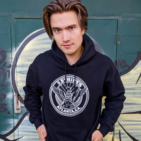 Model wearing a black 5 Stripes City Seal hoodie with phoenix emblem graphic inspired by Atlanta’s rise
