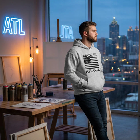Man wearing a heather gray Made in Atlanta hoodie with a bold graphic on the front, with the Atlanta cityscape behind him