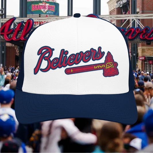 Baseball cap with 'Believers' and bat design in front of a crowd at a stadium.